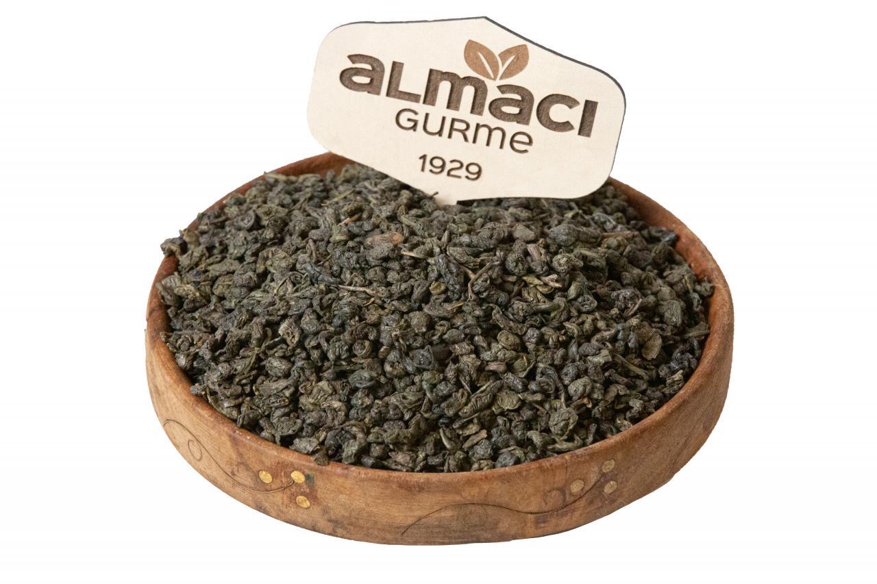Ahşap bir kasede, yaprakları top şeklinde kıvrılmış yeşil seylan çay bulunuyor.