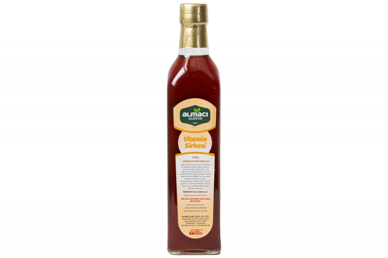 500 ml'lik altın kapaklı cam şişede vitamin sirkesi bulunuyor. Etiketinde "Doğal Sirke", "Vitamin Sirkesi" yazıyor, çevre basit ve beyaz.