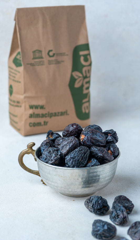 Elde tutulan Acve hurması ve arka planda Türk kahvesi, Peygamber hurması olarak bilinen siyah renkli, yuvarlak ve şifalı Medine hurması.