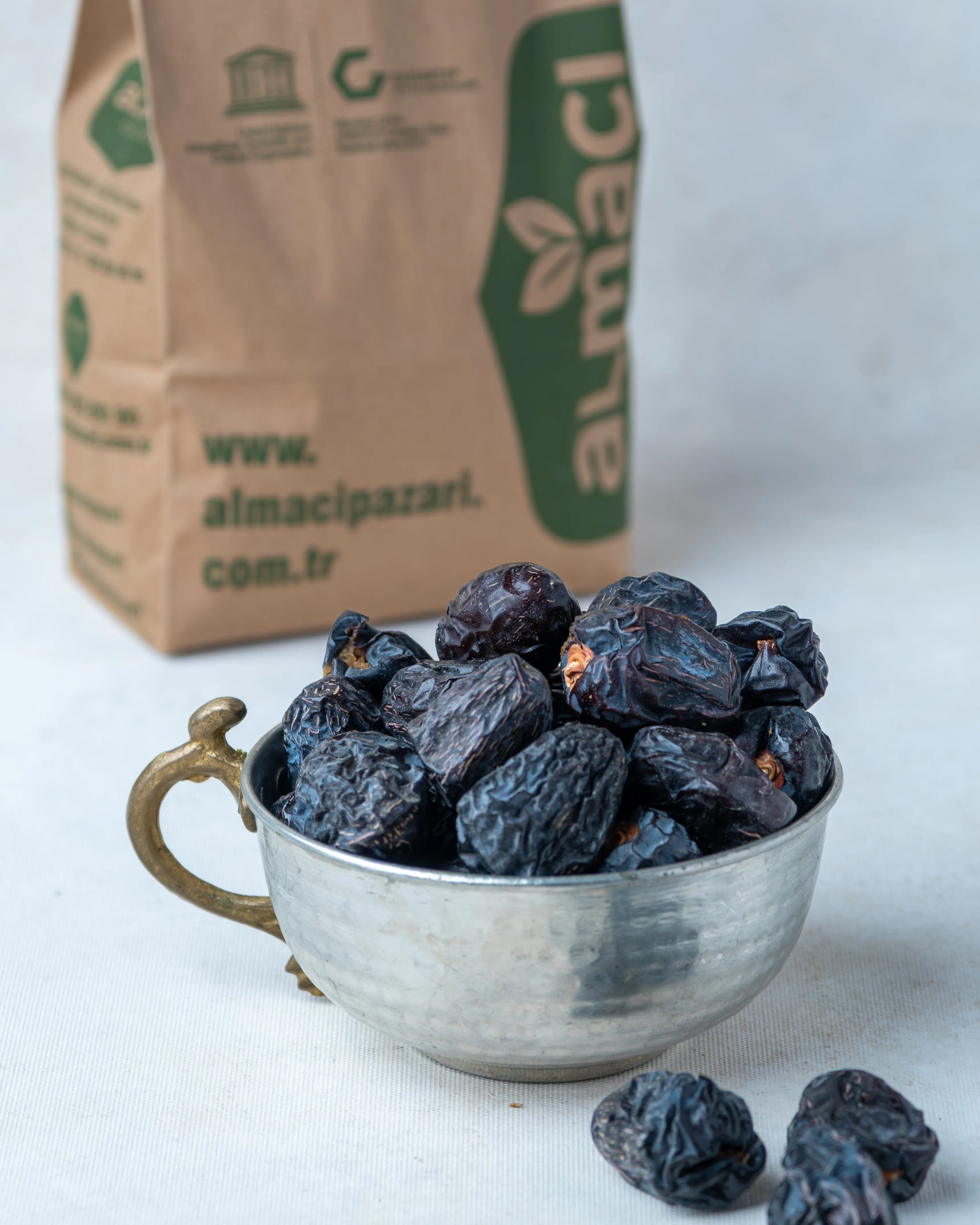 Elde tutulan Acve hurması ve arka planda Türk kahvesi, Peygamber hurması olarak bilinen siyah renkli, yuvarlak ve şifalı Medine hurması.