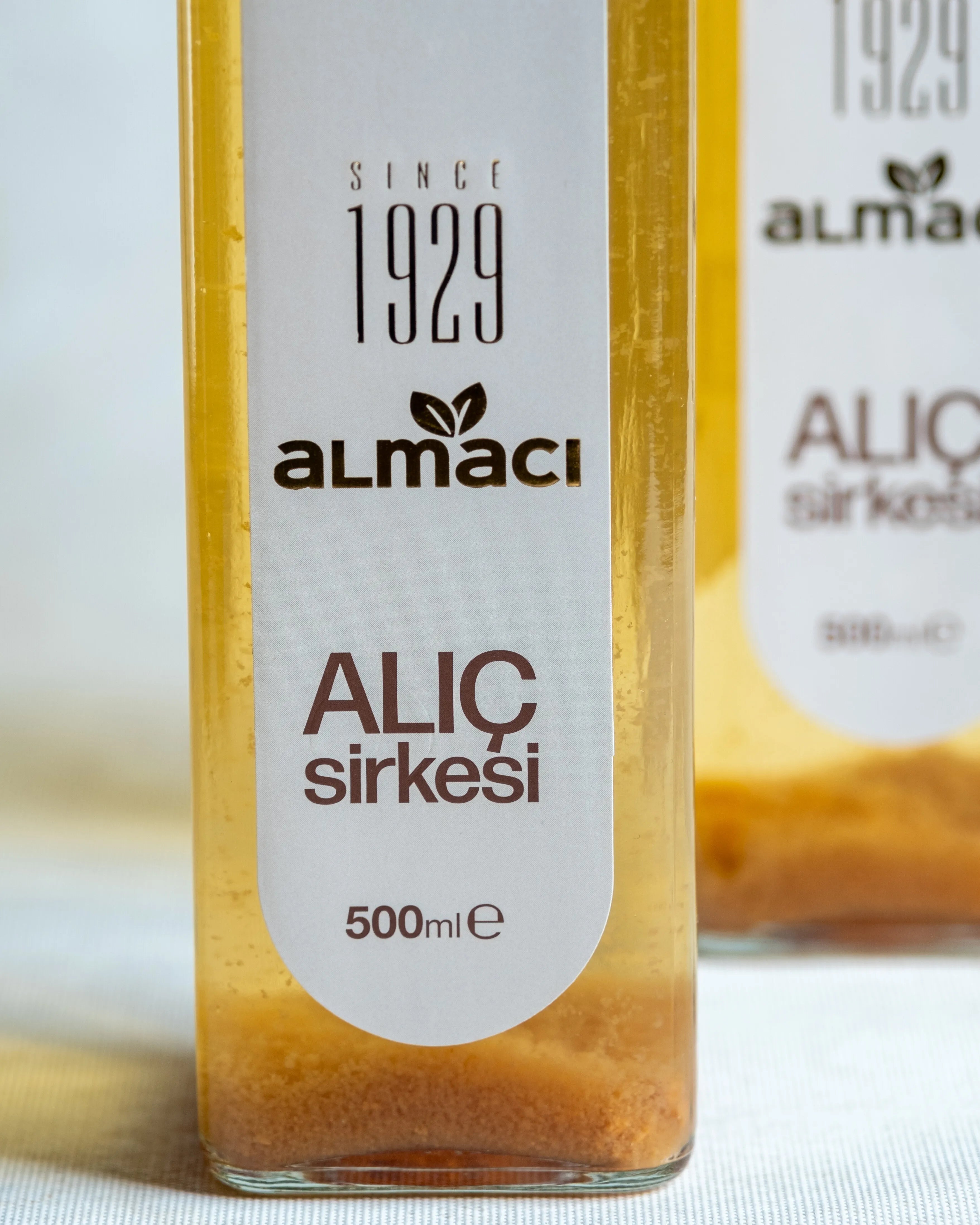 Almacı Pazarı alıç sirkesi yakın çekim; 500 ml cam şişede sirke anası ve doğal tortusu görünen geleneksel fermente alıç sirkesi.