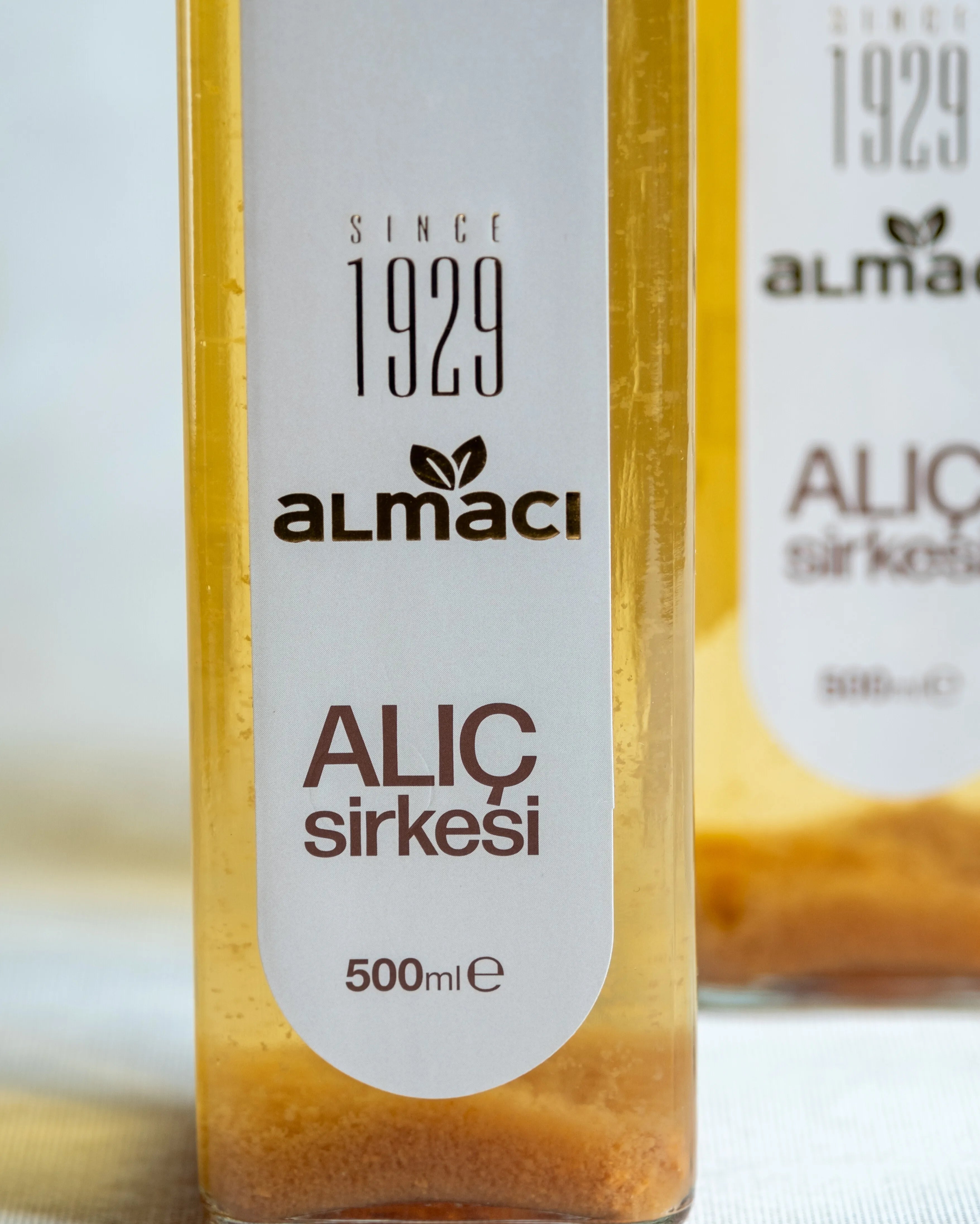 Almacı Pazarı alıç sirkesi yakın çekim; 500 ml cam şişede sirke anası ve doğal tortusu görünen geleneksel fermente alıç sirkesi.