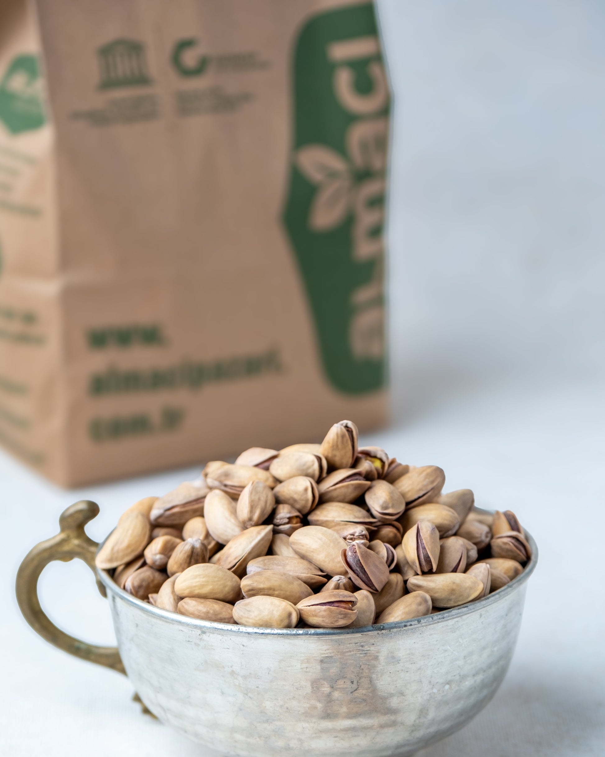 Yakından görünüm metal kasede Antep fıstığı, dalında kendiliğinden açılan ana çıtlak, az tuzlu ve çifte kavrulmuş taze mahsül.