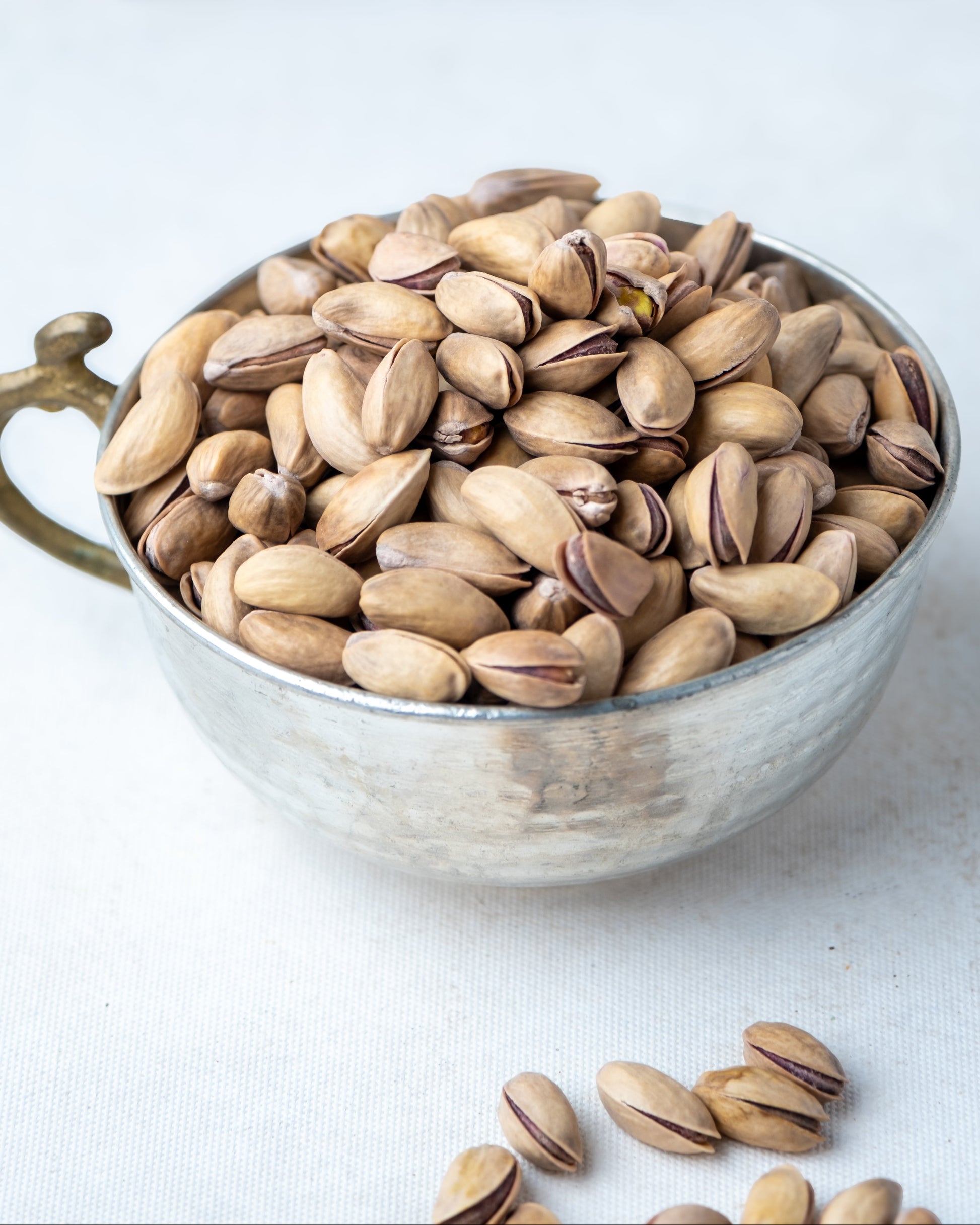 Yakından görünüm metal kasede Antep fıstığı, dalında kendiliğinden açılan ana çıtlak, az tuzlu ve çifte kavrulmuş taze mahsül.