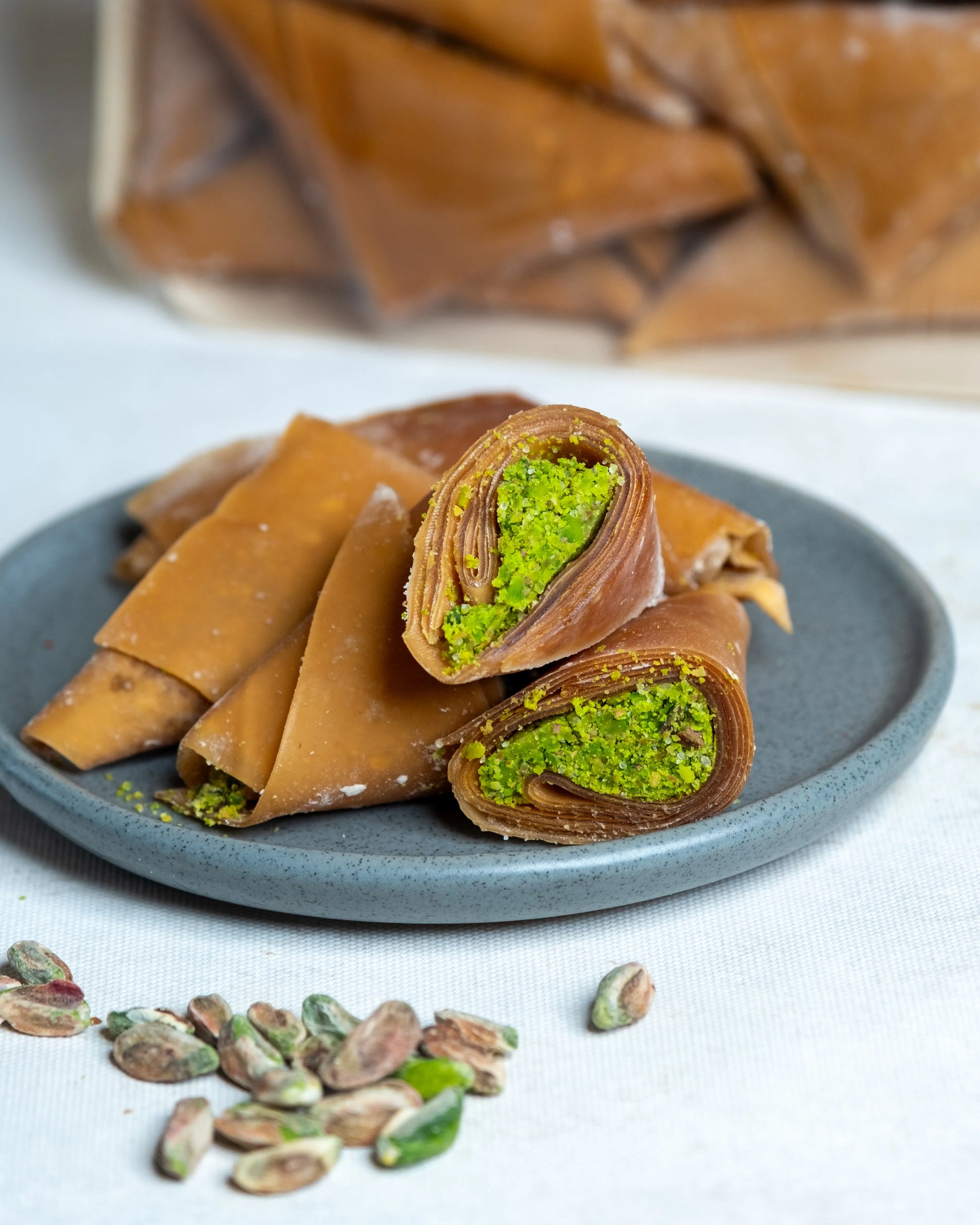 Tabakta sunulan fıstıklı muska ve sarmalar, incecik meyve pestili içine sarılmış bol Antep fıstıklı geleneksel yöresel tatlı.