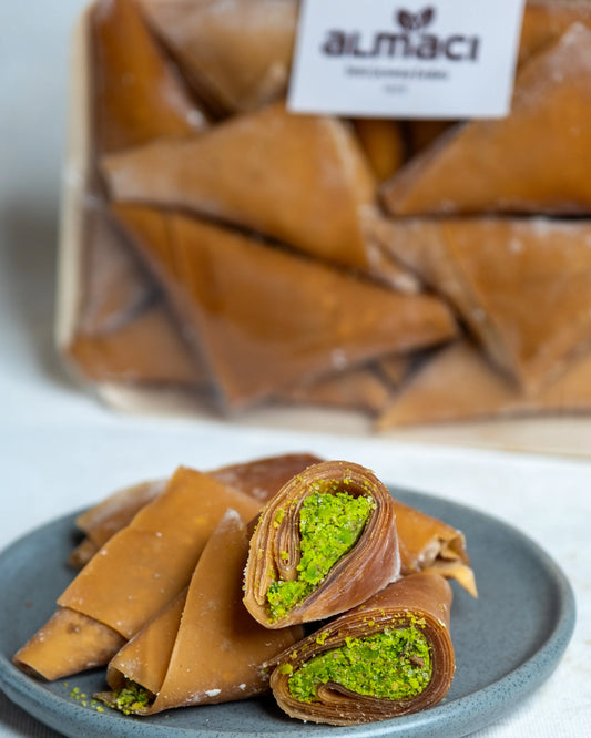 Tabakta sunulan fıstıklı muska ve sarmalar, incecik meyve pestili içine sarılmış bol Antep fıstıklı geleneksel yöresel tatlı.