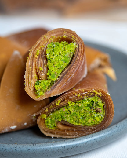 Tabakta sunulan fıstıklı muska ve sarmalar, incecik meyve pestili içine sarılmış bol Antep fıstıklı geleneksel yöresel tatlı.