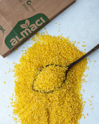 Yakından görünüm tahta kaşıkta sarı pilavlık bulgur, parlak altın rengi ve orta irilikte, domatesli pilav yapımı için doğal durum buğdayı.