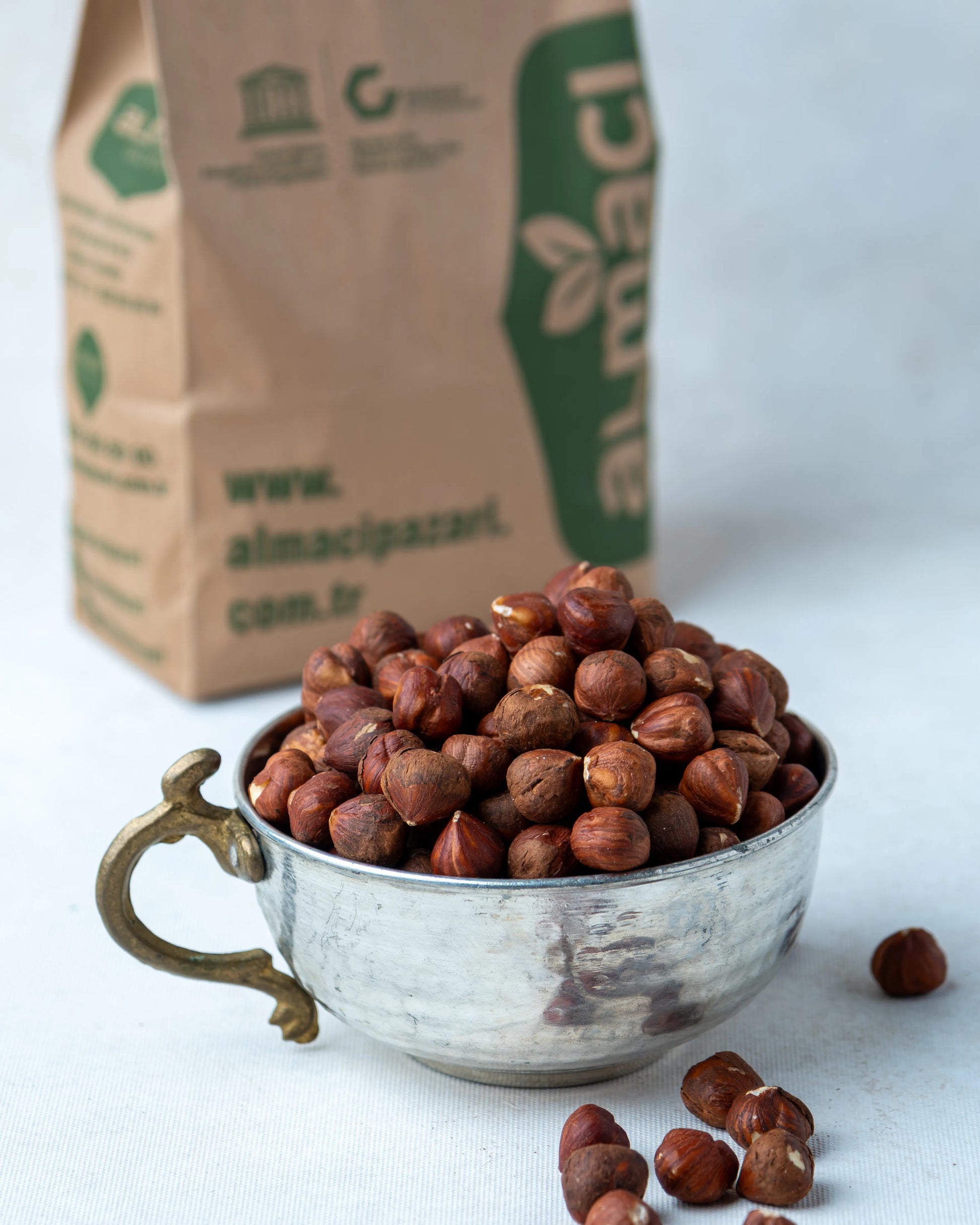 Metal kasede sunulan çiğ fındık içi ve arkada Almacı Pazarı paketi, kavrulmamış ve tuzsuz, yüksek yağ oranlı Giresun kalite doğal kuruyemiş.