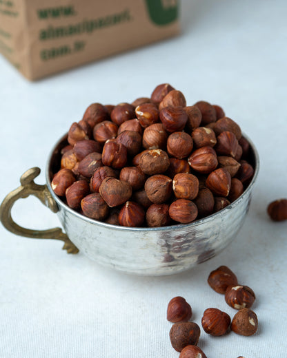 Metal kasede sunulan çiğ fındık içi ve arkada Almacı Pazarı paketi, kavrulmamış ve tuzsuz, yüksek yağ oranlı Giresun kalite doğal kuruyemiş.