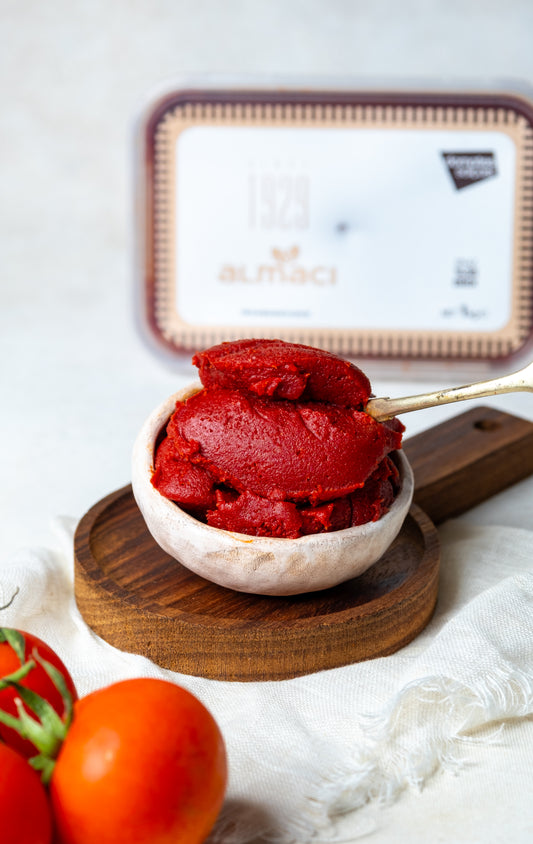 Yakından görünüm kasede domates salçası, kaşıkta iz bırakan yoğun kıvamı ve parlak kırmızı rengiyle güneşte kurutulmuş doğal lezzet.