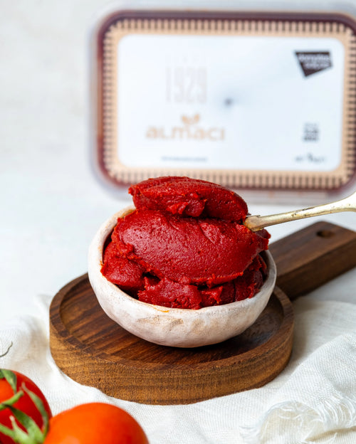 Yakından görünüm kasede domates salçası, kaşıkta iz bırakan yoğun kıvamı ve parlak kırmızı rengiyle güneşte kurutulmuş doğal lezzet.