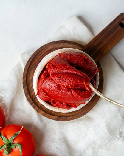 Yakından görünüm kasede domates salçası, kaşıkta iz bırakan yoğun kıvamı ve parlak kırmızı rengiyle güneşte kurutulmuş doğal lezzet.