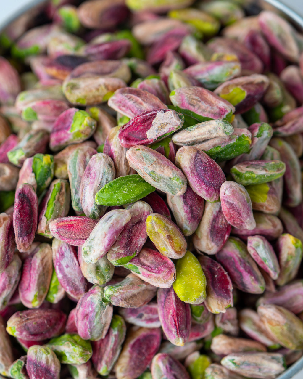 Yakından görünüm kırmızı iç Antep fıstığı, pembe zarlı ve yeşil içli tam olgunlaşmış ayıklanmış kuruyemiş taneleri.