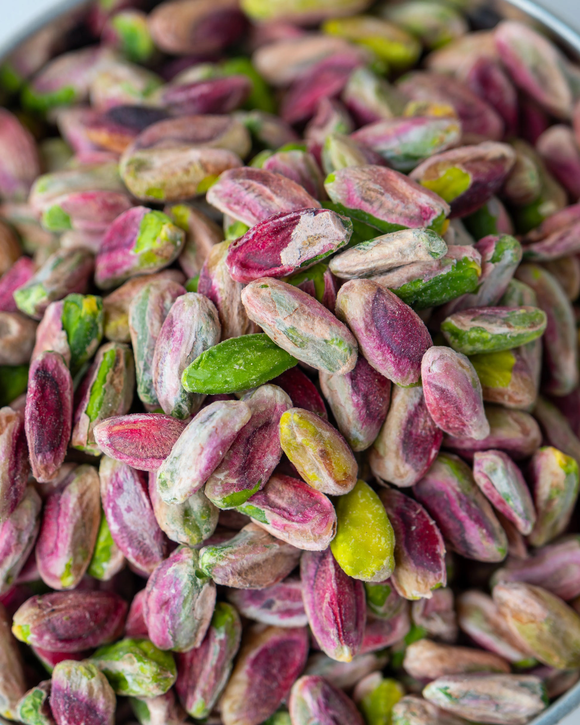 Yakından görünüm kırmızı iç Antep fıstığı, pembe zarlı ve yeşil içli tam olgunlaşmış ayıklanmış kuruyemiş taneleri.