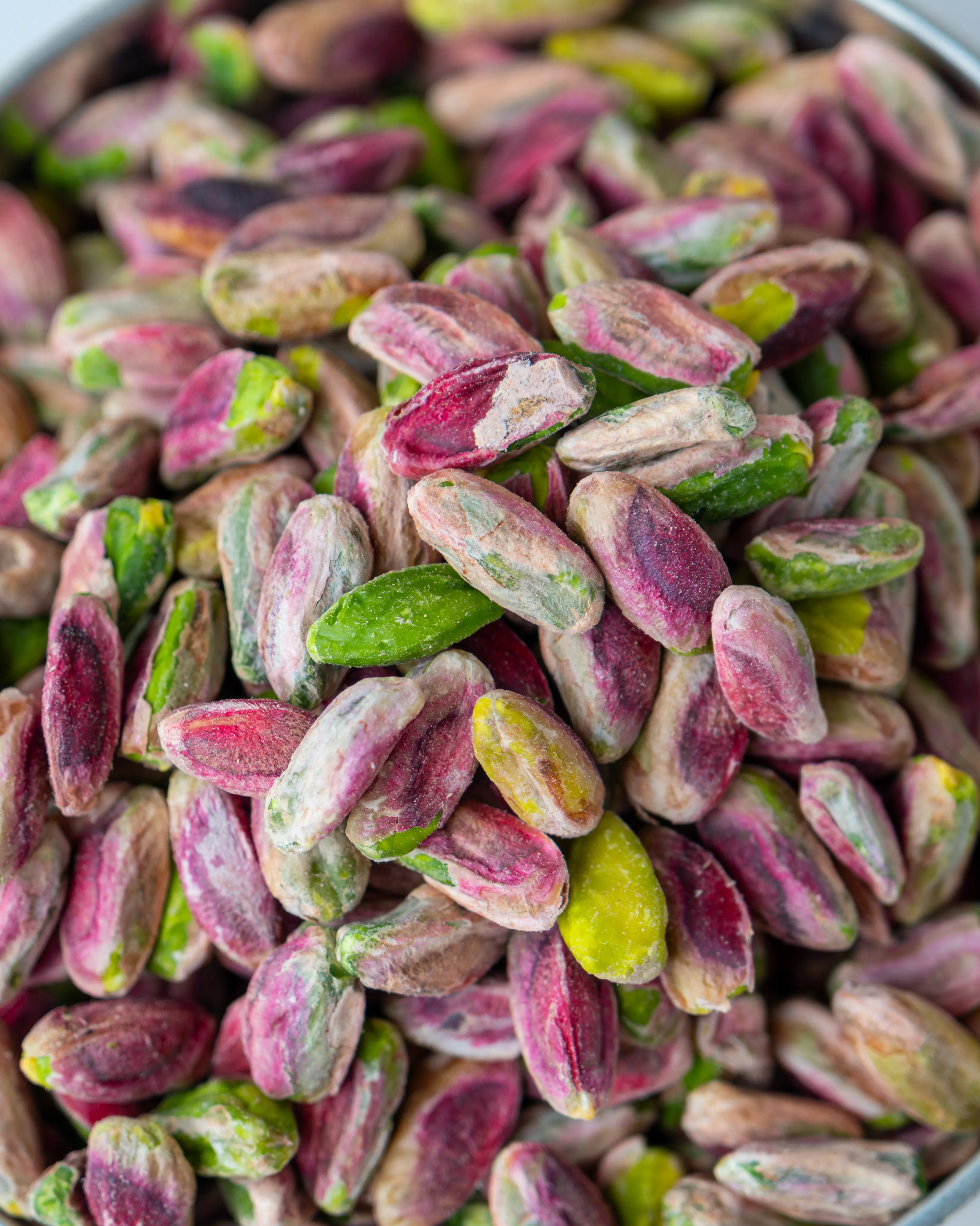 Yakından görünüm kırmızı iç Antep fıstığı, pembe zarlı ve yeşil içli tam olgunlaşmış ayıklanmış kuruyemiş taneleri.