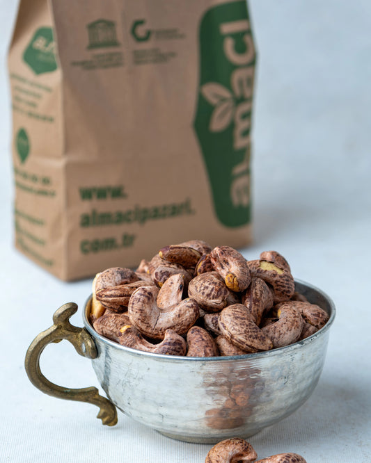 Yakından görünüm kabuklu kaju, üzerindeki ince kahverengi zarı ile kavrulmuş, soyularak yenen yoğun aromalı tuzlu fıstık.