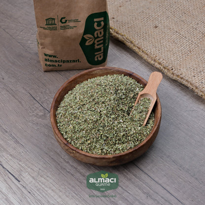 Ahşap bir kapta kekik ve küçük bir tahta kaşık duruyor. 