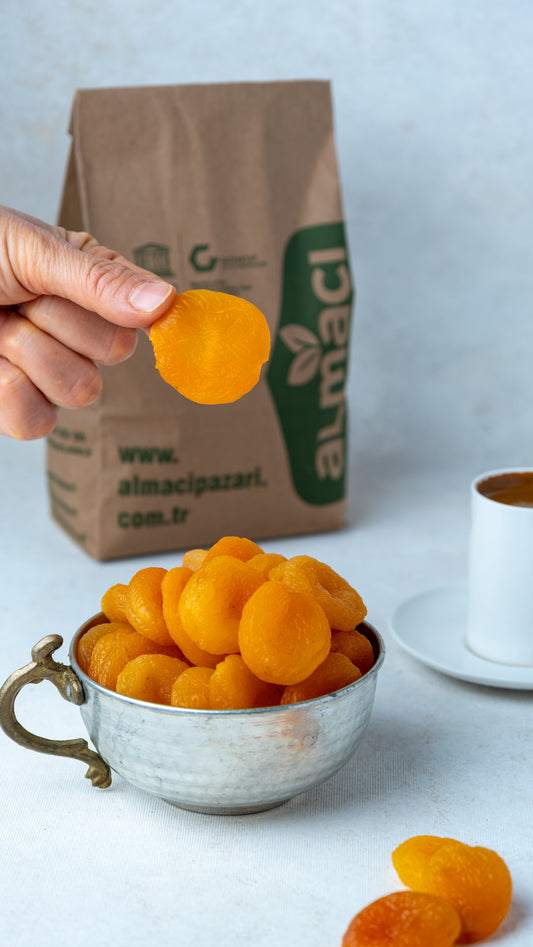 Elde tutulan sarı kuru kayısı ve arka planda Türk kahvesi, Malatya'nın meşhur islimli ve şekerpare cinsi, tatlı ve yumuşak kuru meyvesi.