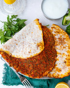 Metal tabakta servis edilen ince hamurlu Gaziantep lahmacunu, yanında bol köpüklü ayran, limon ve taze yeşilliklerle sunulan taş fırın lezzeti.