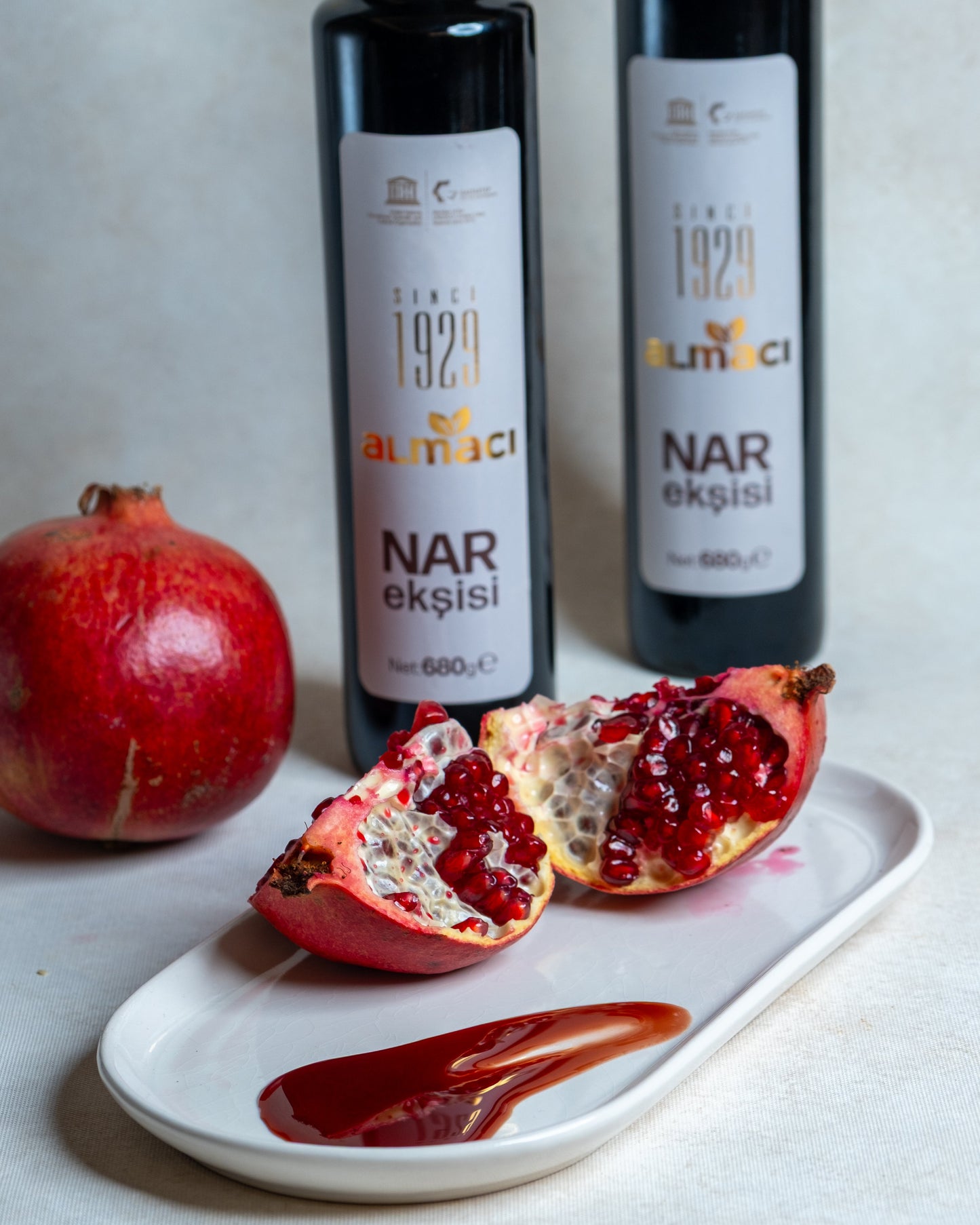 Beyaz tabakta koyu kıvamlı nar ekşisi sunumu ve taze nar, salatalar ve çiğ köfte için katkısız doğal nar suyu konsantresi.