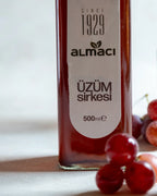 İki şişe Almacı Pazarı üzüm sirkesi ve taze kırmızı üzümler, salata ve turşular için kehribar renkli doğal fermente sirke.