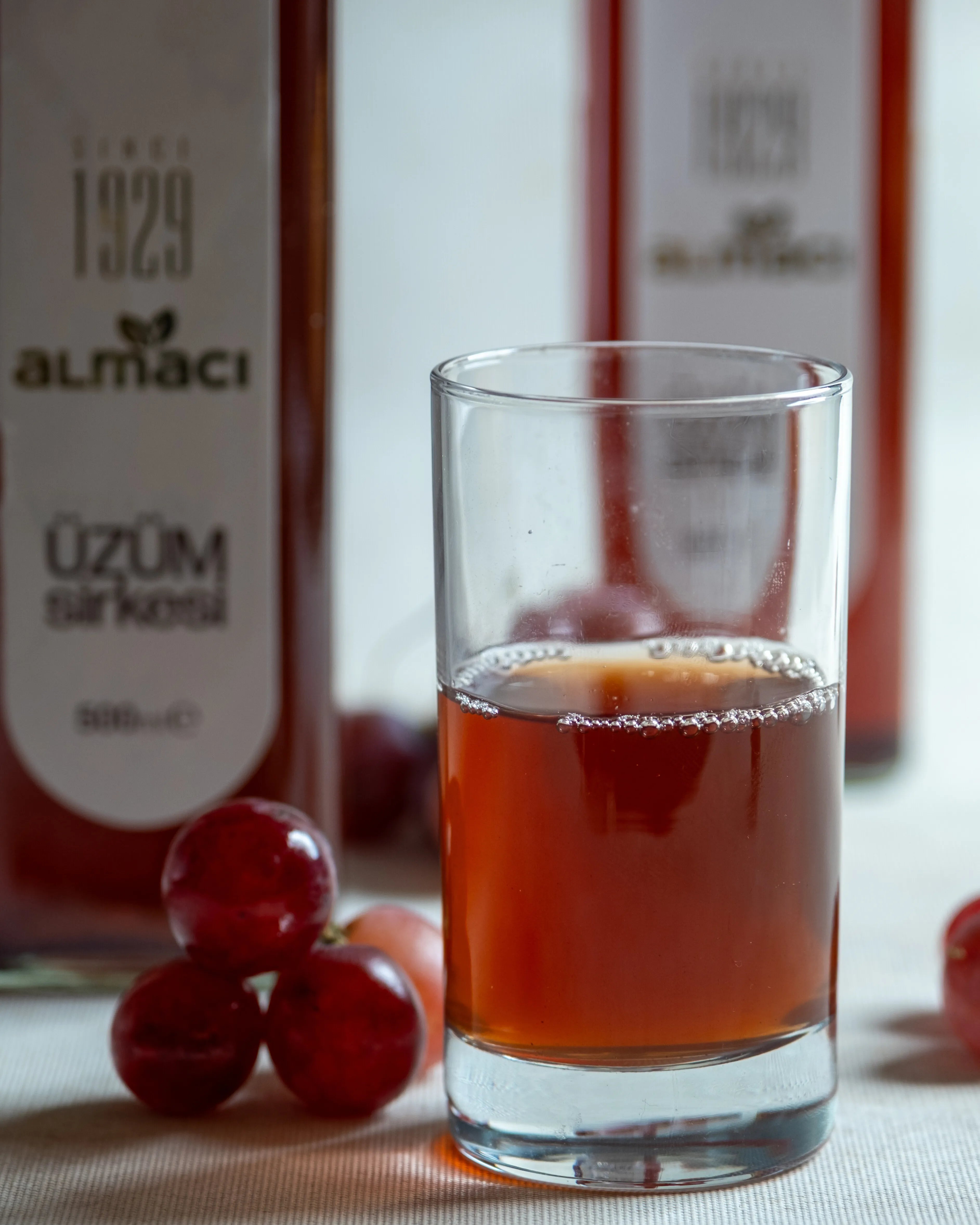 İki şişe Almacı Pazarı üzüm sirkesi ve taze kırmızı üzümler, salata ve turşular için kehribar renkli doğal fermente sirke.