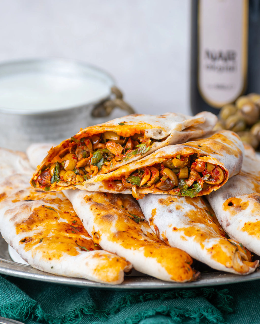 İkiye bölünmüş zeytinli börek, içinde dilimlenmiş yeşil zeytin, ceviz ve nar ekşili özel harç bulunan, taş fırında pişmiş Gaziantep kahvaltılığı.