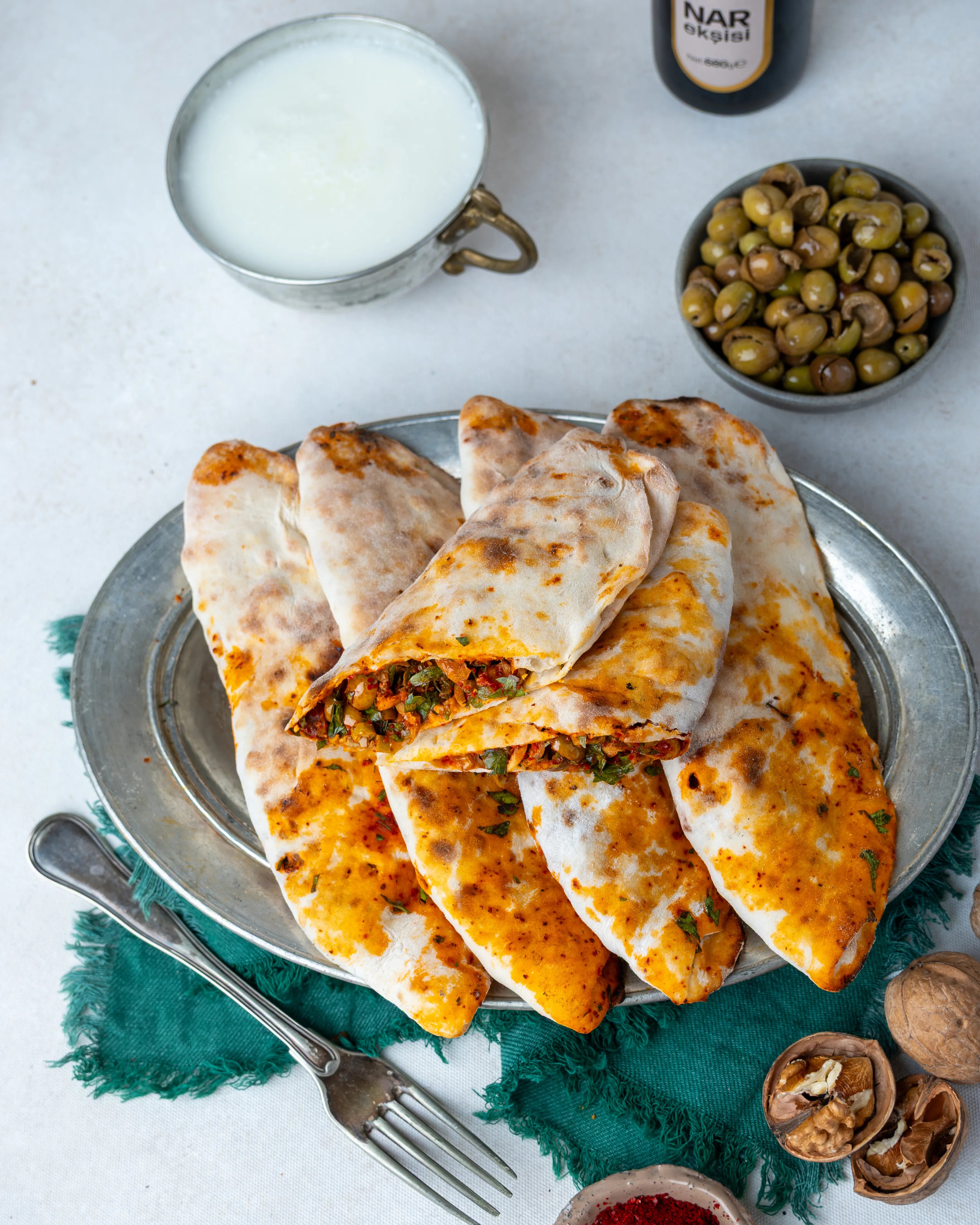 İkiye bölünmüş zeytinli börek, içinde dilimlenmiş yeşil zeytin, ceviz ve nar ekşili özel harç bulunan, taş fırında pişmiş Gaziantep kahvaltılığı.